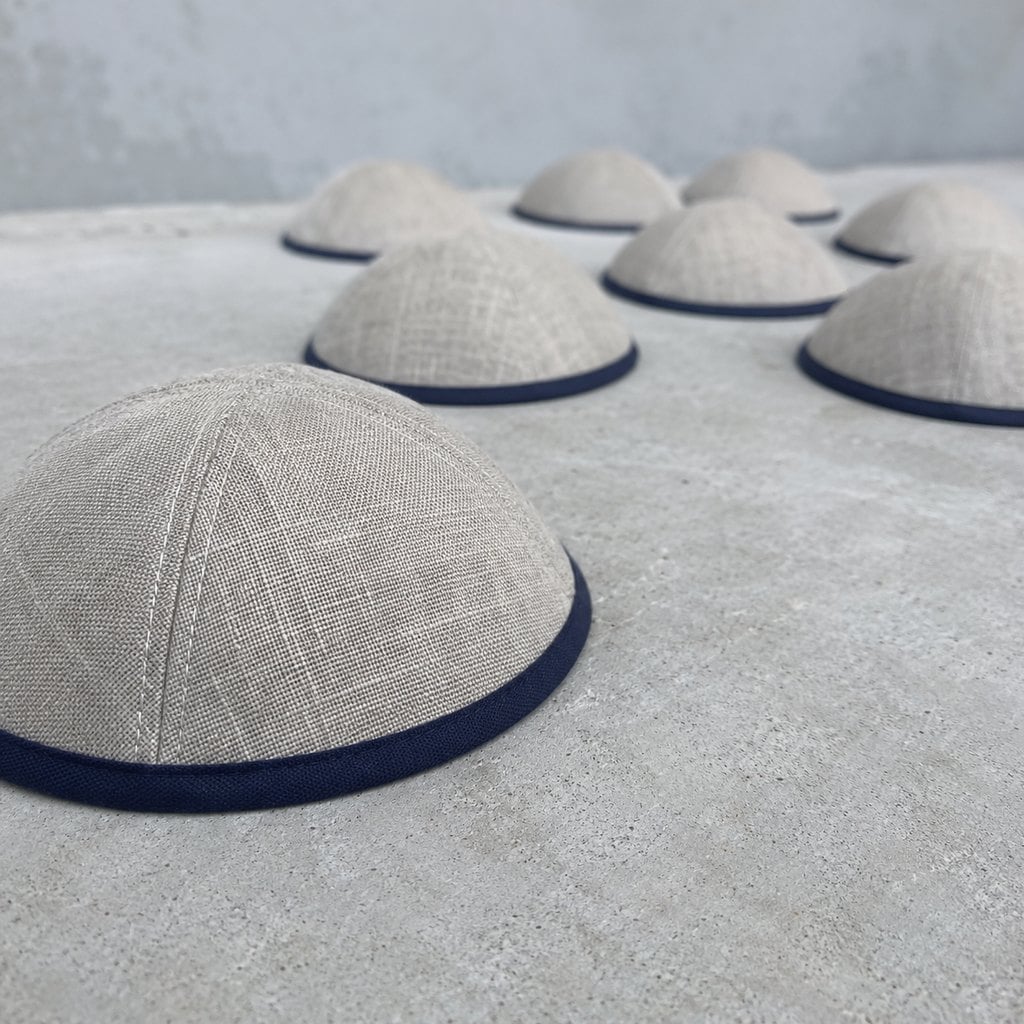 Custom linen kippahs with navy trim on a concrete table